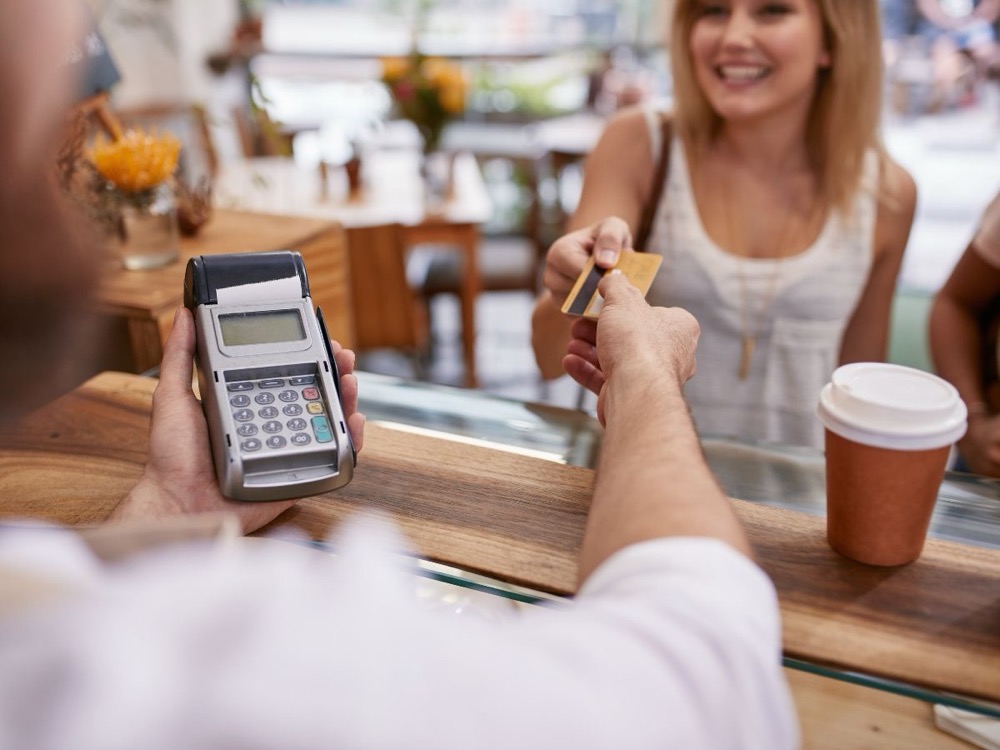 Cashier holding a handheld card terminal for a customer