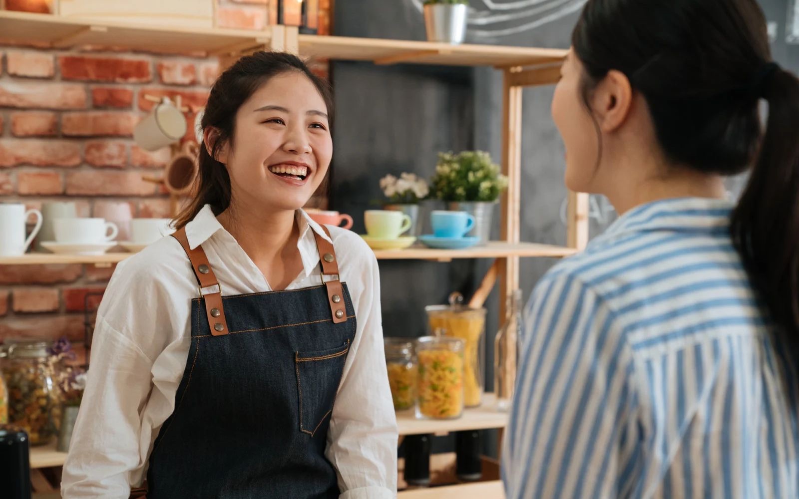 Shop owner laughing with a customer across the counter