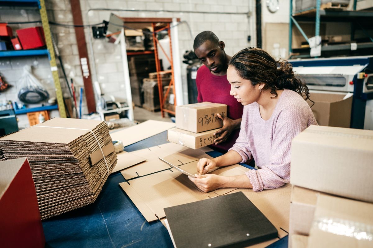 Two business owners checking an order while packing boxes in their warehouse