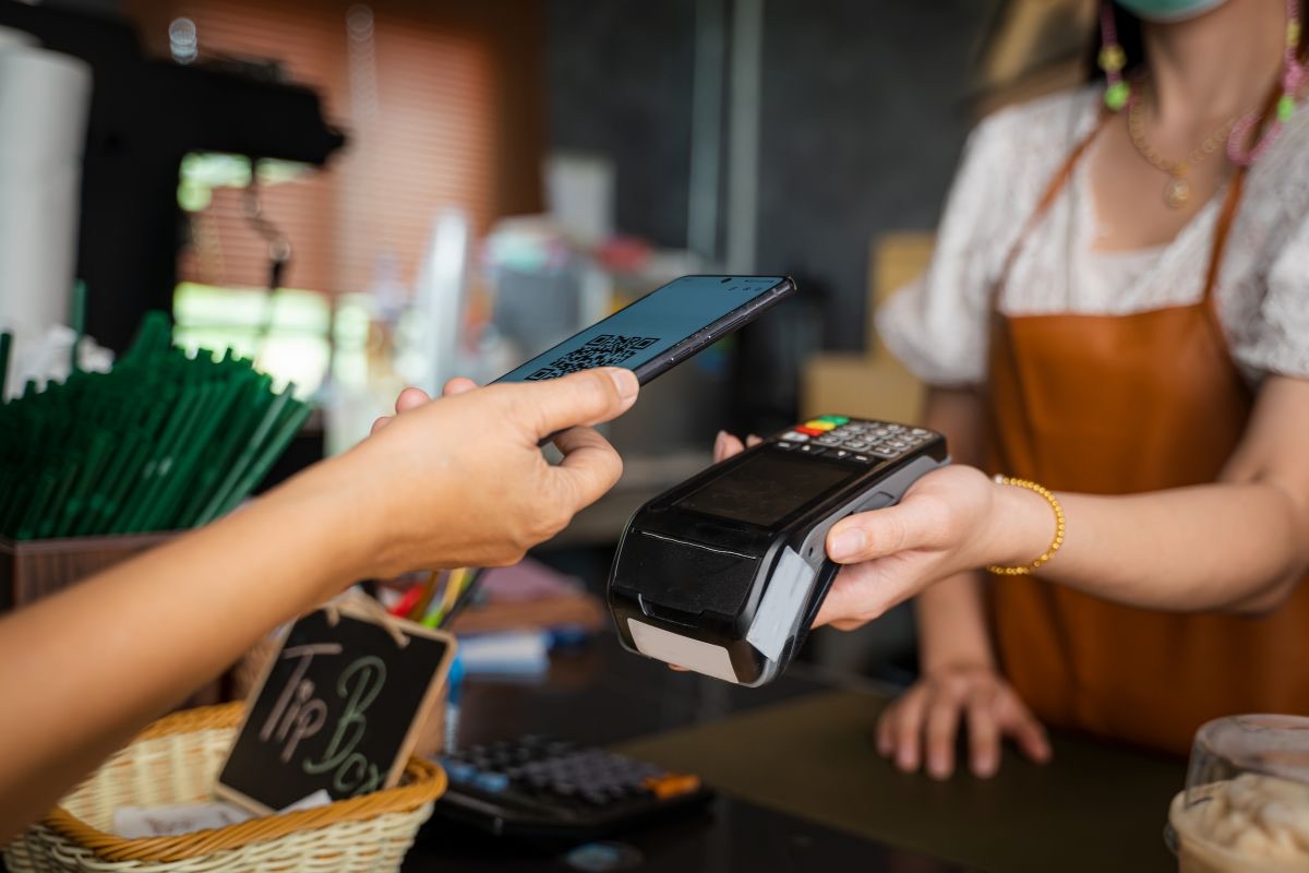 Customer paying with a phone at a card terminal in a café